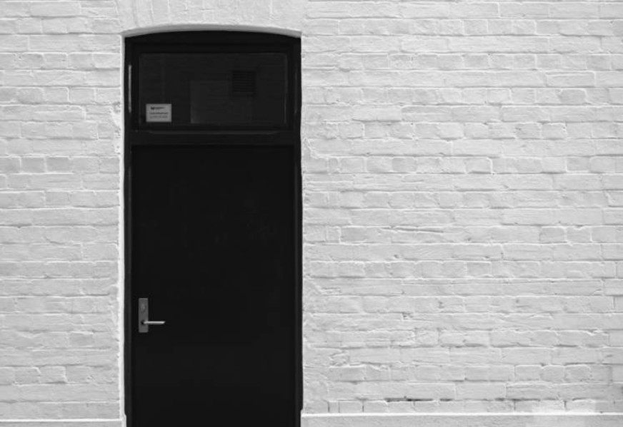Diferencia entre puerta negra blindada y acorazada en pared gris
